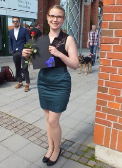 Student standing with a rose in her hand on graduation day