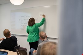 En person står framför en whiteboard och skriver.