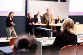  En grupp människor som sitter vid bord framför en projektorskärm.