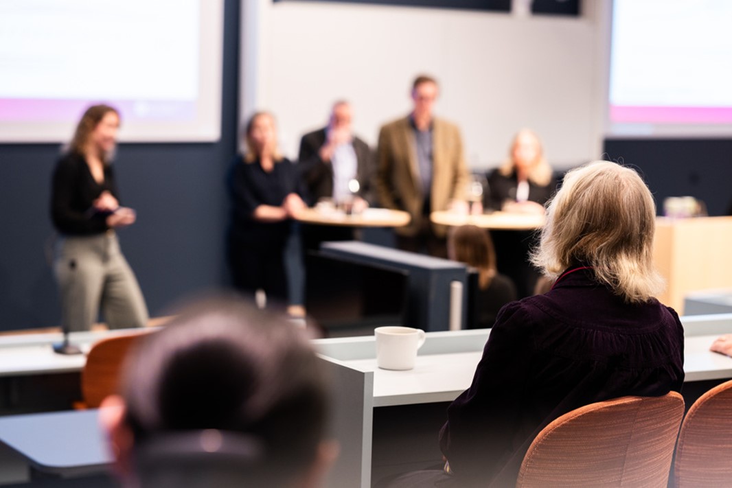  En grupp människor som sitter vid bord framför en projektorskärm.