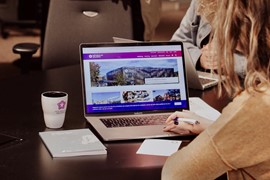 En person sittandes vid ett bord med en laptop framför sig