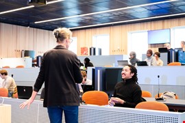 Lärare som står i ett klassrum framför studenter