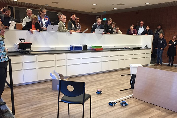 Konferensdeltagare tittar på en 5-kamp med robotar