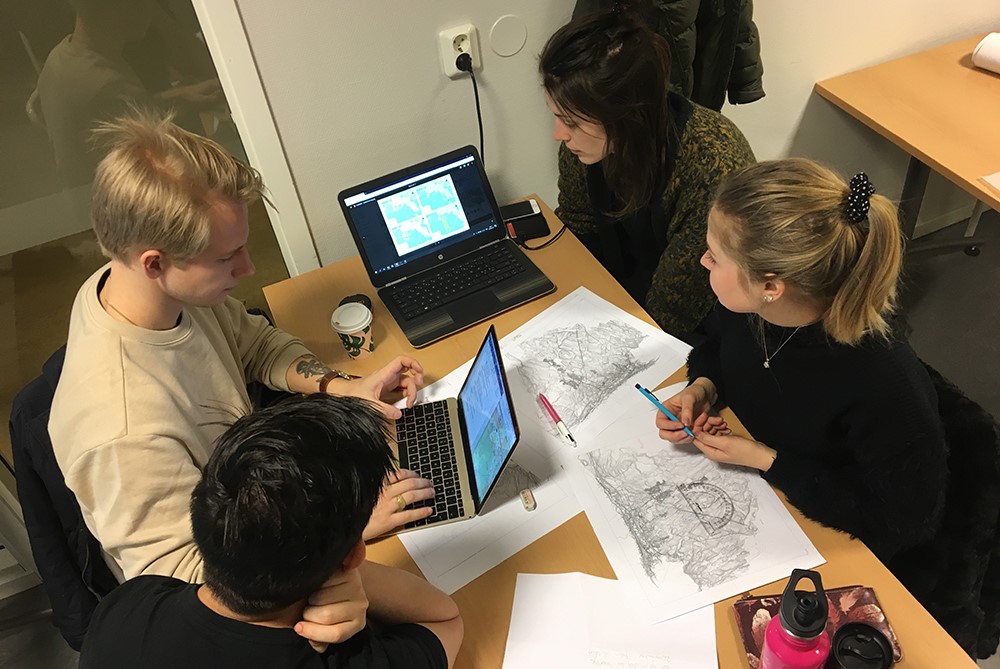 Fyra studenter jobbar med ritningar och datorer
