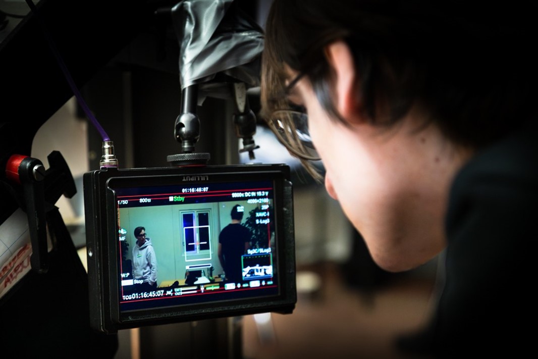 Bild på person som tittar genom videokamera.