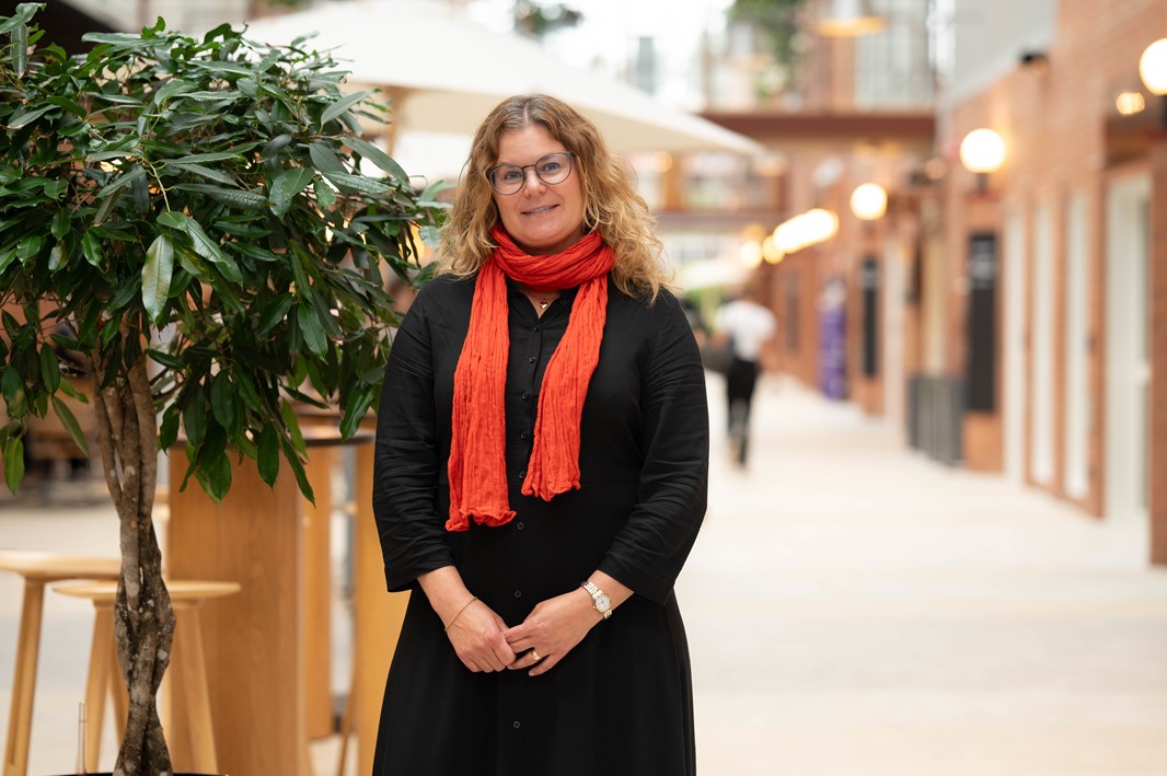 Person står inomhus långt hår glasögon halsduk klänning