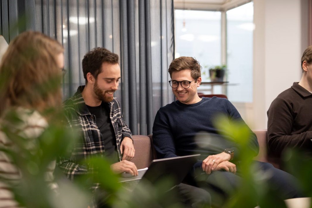 Två personer sitter i en soffa och tittar på en dator.
