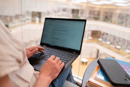 Student som sitter i biblioteket i Falun och arbetar på sin laptop.