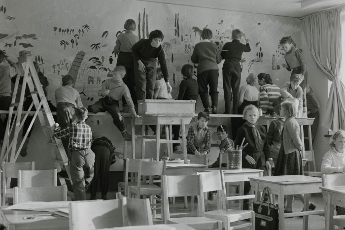 Elever skapar en väggmålning tillsammans i ett klassrum.