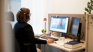 En peson i svarta kläder sitter framför en dator 