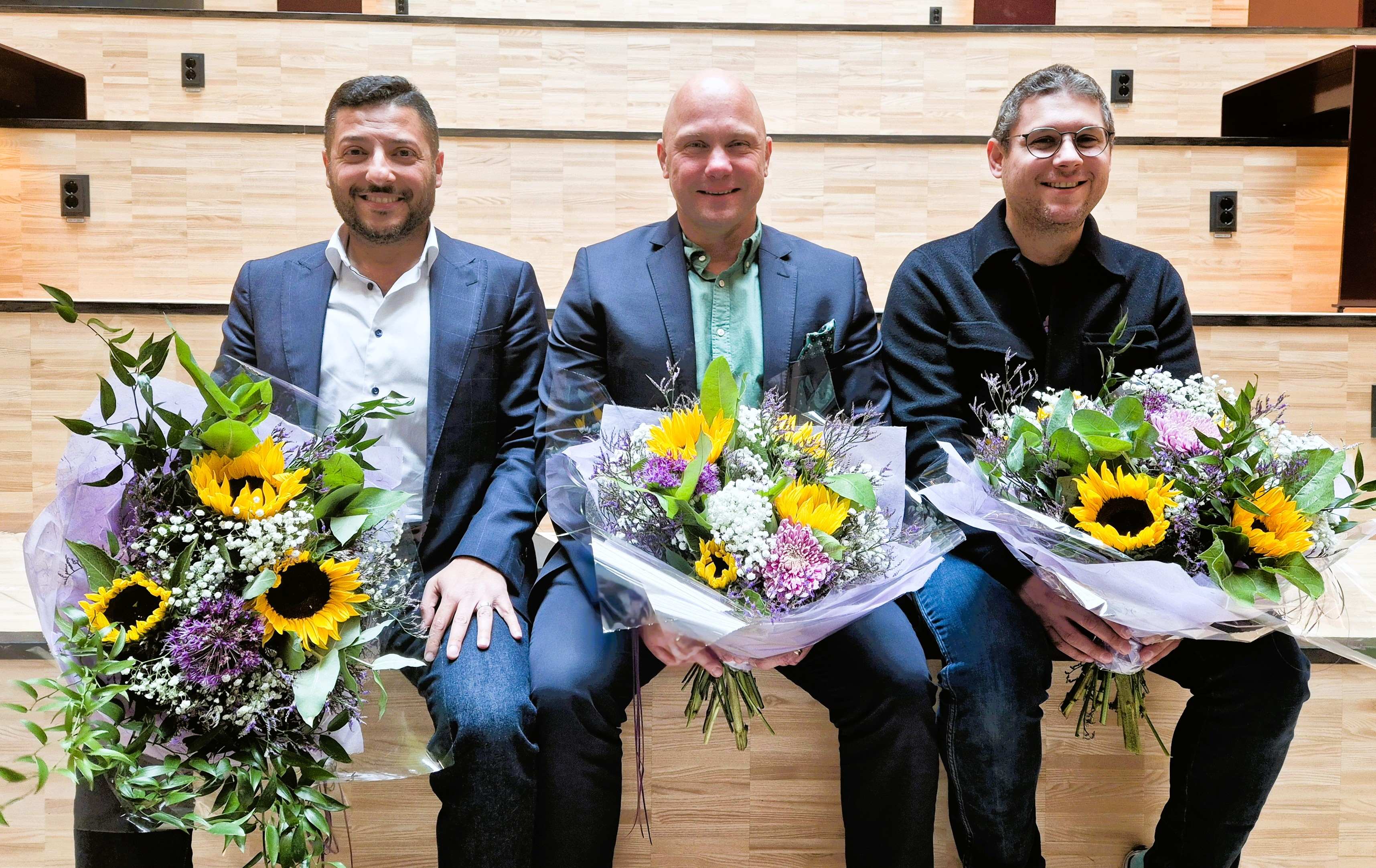 Three people sitting on a staircase holding bouquets of flowers