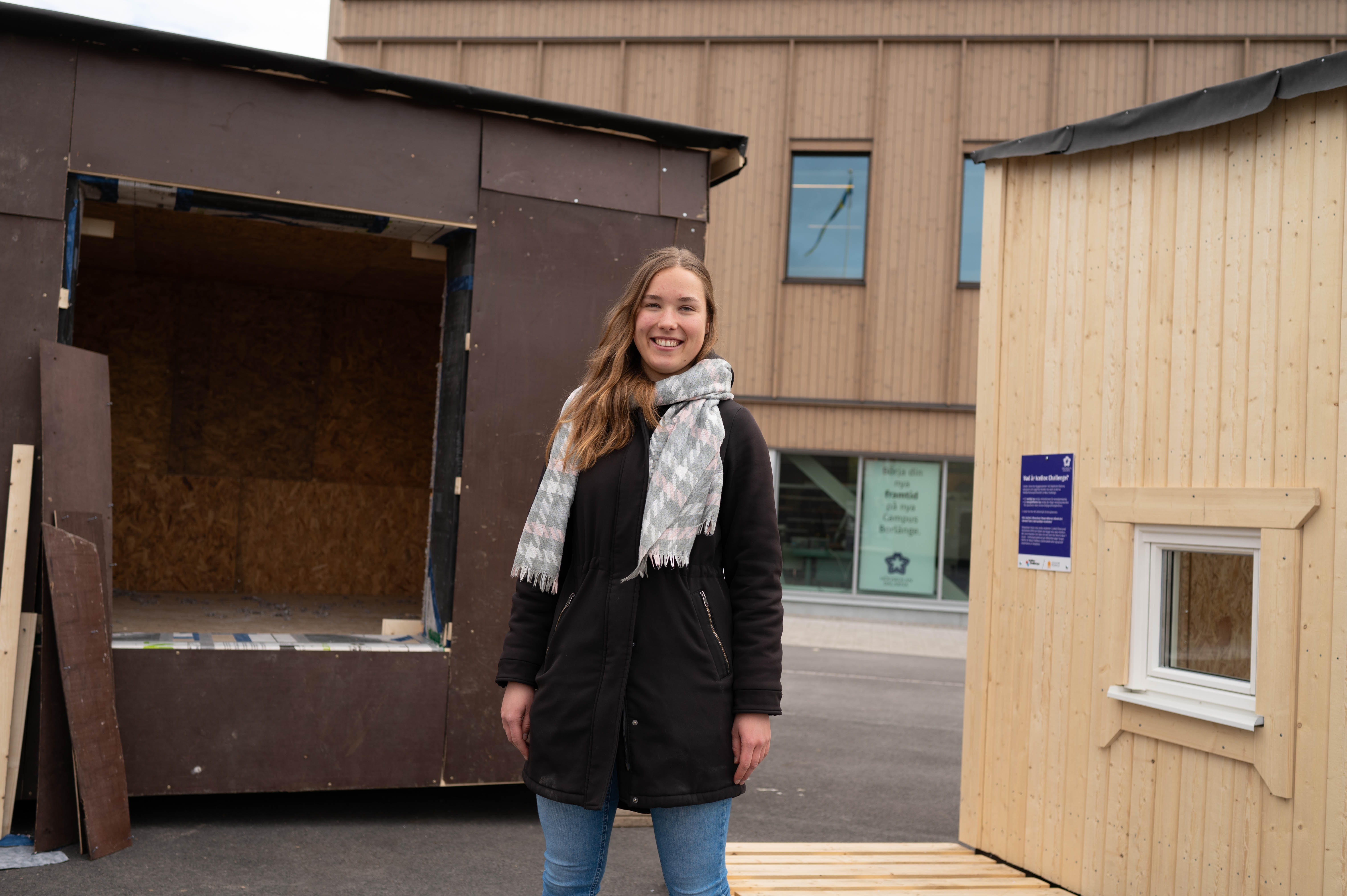 En bild på en student, Mascha Drogt, som står framför de två minihusen. 
