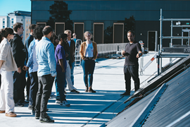 André Augusto stands beside the solar PV installation on the Borlänge campus, explaining research and teaching to a group of people.