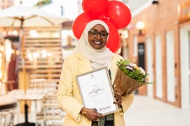 Kvinna ler glasögon klänning slöja diplom bukett ballonger står inomhus