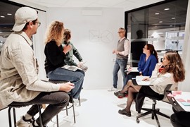 Grupp personer inomhus några står, några sitter workshop.