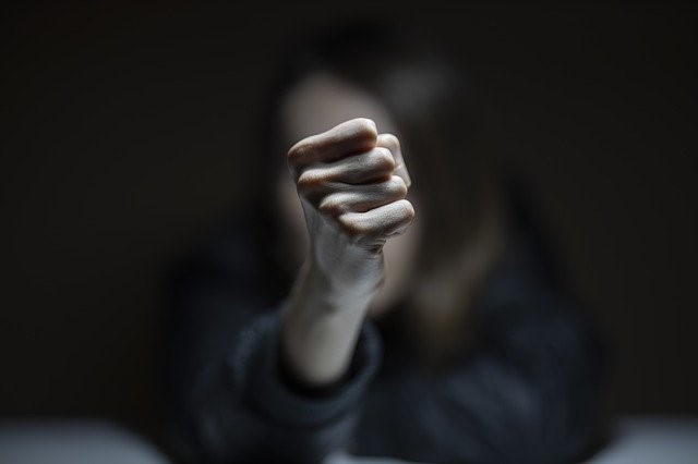 Knuten hand, människa suddigt i bakgrunden.