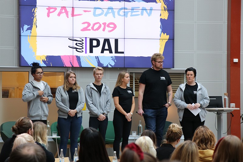 Group of people on the stage in front of a screen showing images related to PAL
