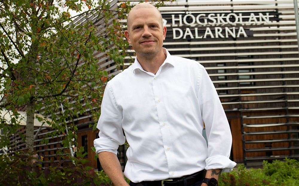 Johan Kostela, samverkansstrateg på Högskolan Dalarna, står i vit skjorta utan för Campus Falun. 