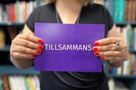 Kvinna som håller i en lila bild som det står tillsammans på