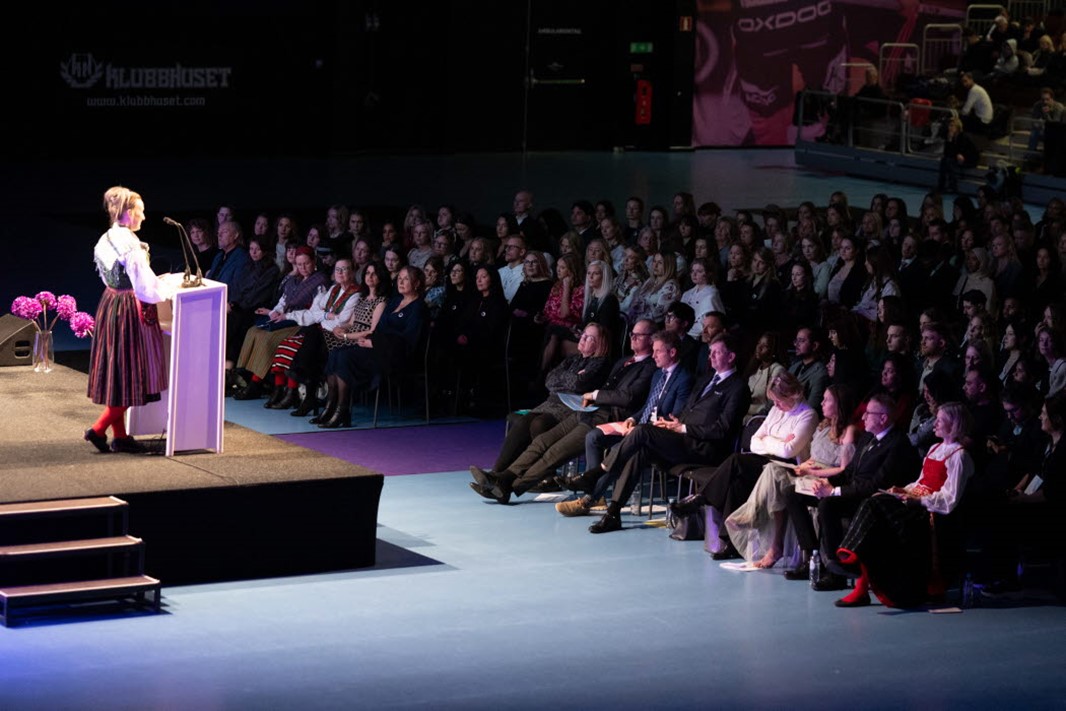 Avslutningsceremoni. En talare framför en talarstol pratar inför en stor publik.