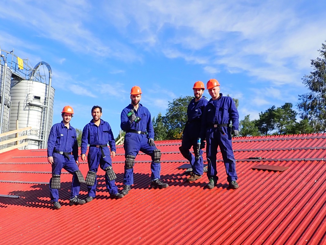 Students working on the roof of a barn to install solar panels