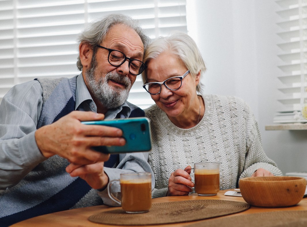 Äldre man och kvinna tittar på mobiltelefon. 