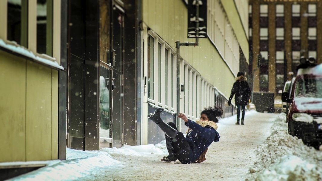 Kvinna halkar på snöig gata. 