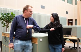 Man och kvinna nuddar varandras armbågar. 