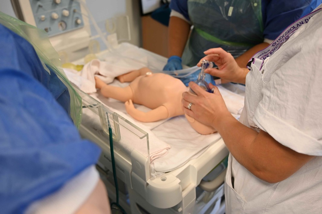 Händer och en docka i sjukhusmiljö