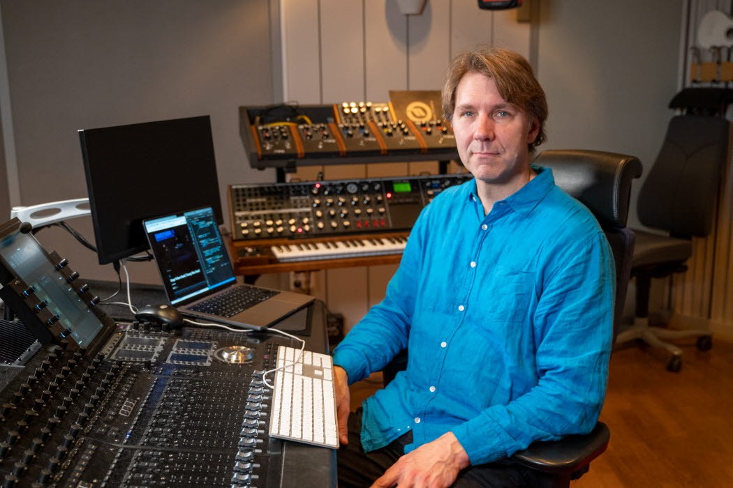 Man i blå skjorta sitter i mediastudio.