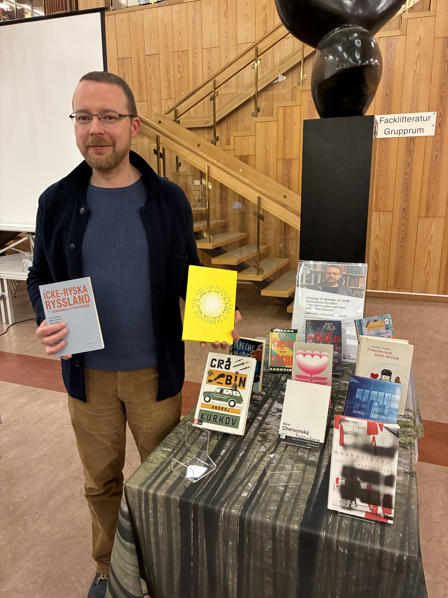 Kostia står vid ett bord med böcker på biblioteket