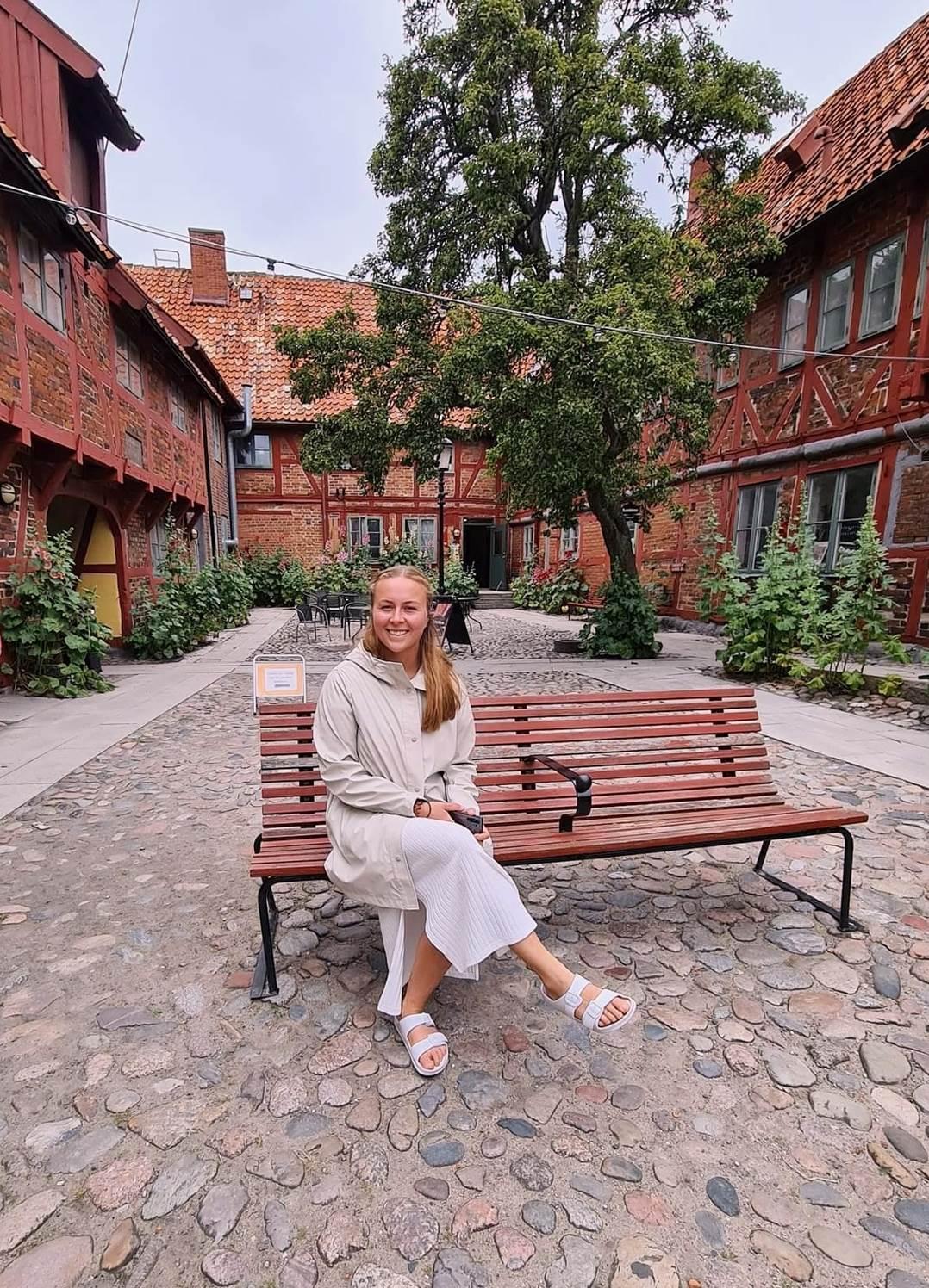 Kristina sitting on a bench in a cobblestone courtyard