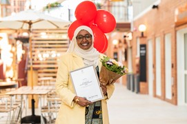 Kvinna  glasögon klänning slöja diplom bukett röda ballongerstår inomhus