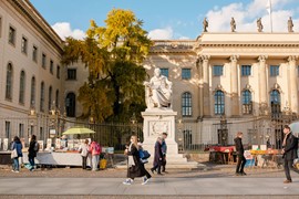 Gatubild på Humboldtuniversitet med marknadsstånd och fotgängare i Berlin.