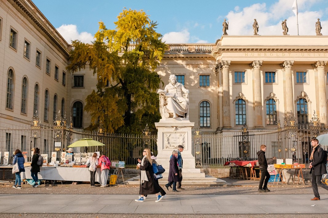 Gatubild på Humboldtuniversitet med marknadsstånd och fotgängare i Berlin.