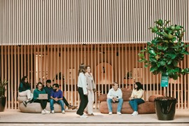  En grupp människor som sitter i soffor framför en byggnad.