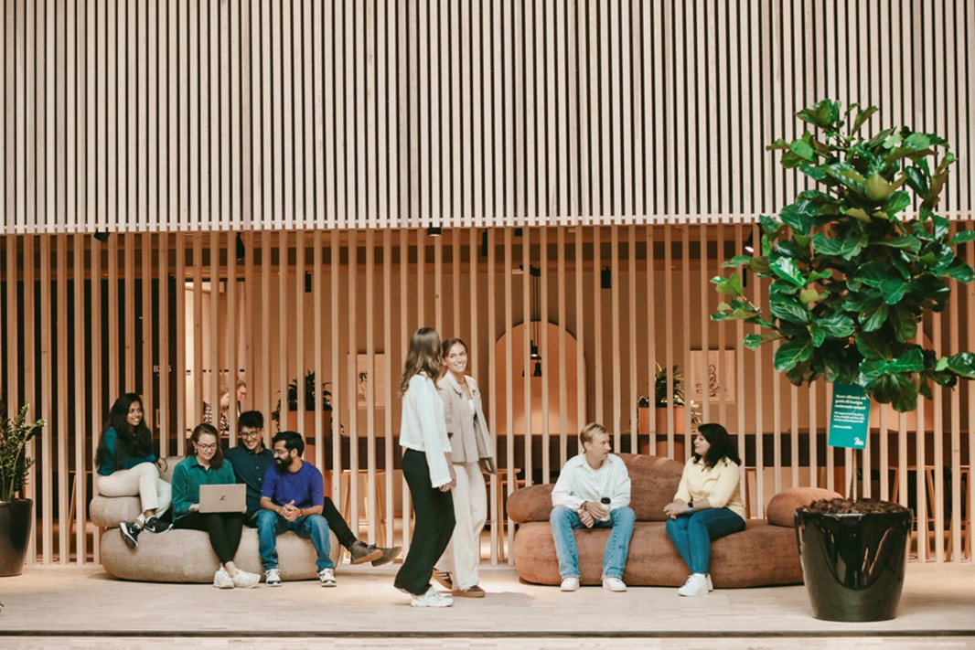  En grupp människor som sitter i soffor framför en byggnad.