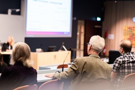 En grupp människor som sitter framför en projektorduk.