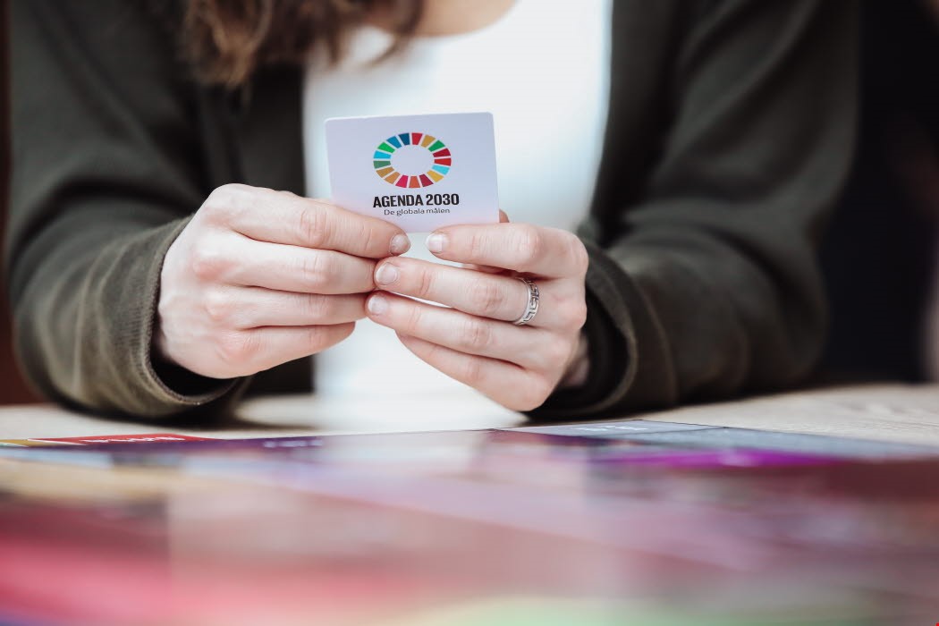Hands holding a game card with the logotype of Agenda 2030