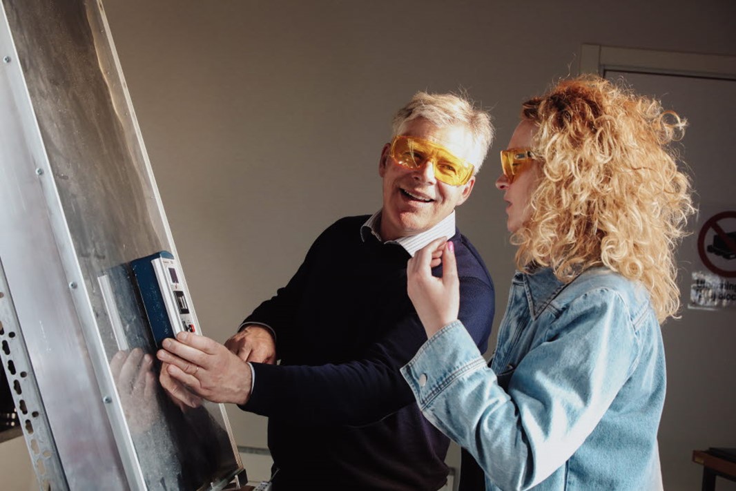 Two persons standing indoors talking