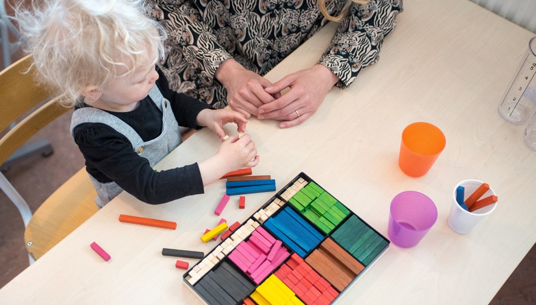 En grupp barn som sitter framför en lärare och en whiteboard.
