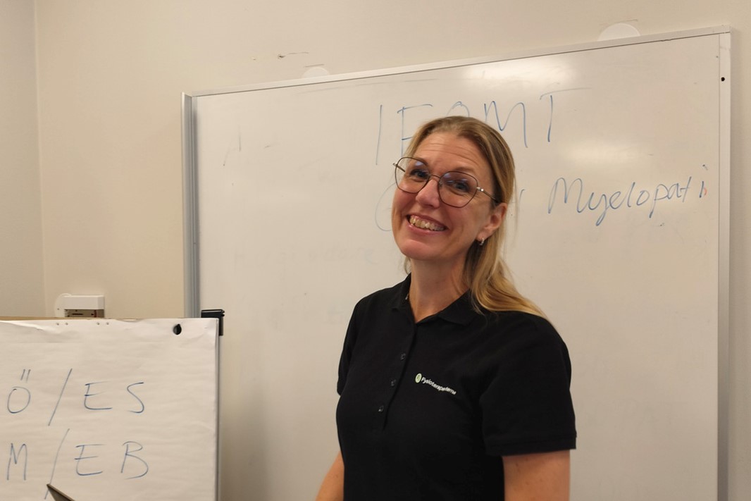 Kvinna står och undervisar framför en whiteboard tavla. 