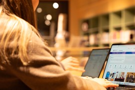 Två personer sitter vid ett bord med bärbara datorer. Fokuset i bilden är på datorerna.