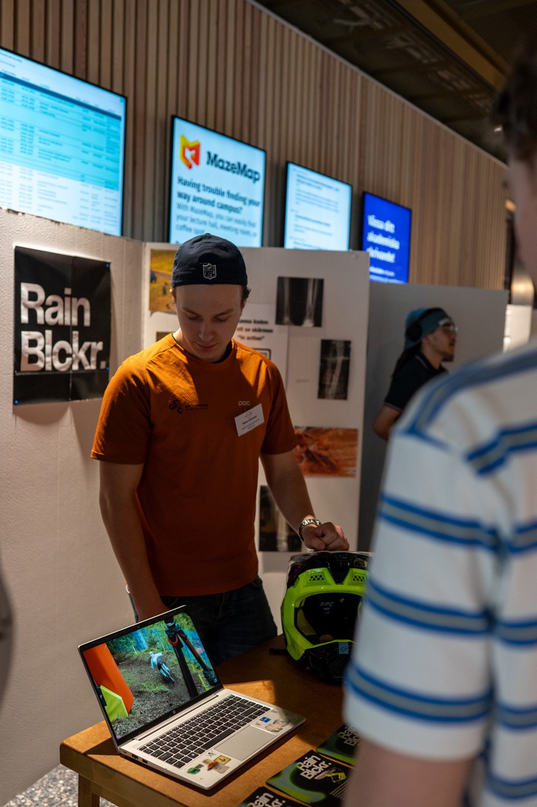En kille står framför en monter och presenterar sin produkt.