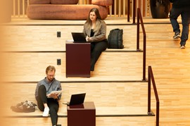 En man och en kvinna sitter på en trappa och studerar.