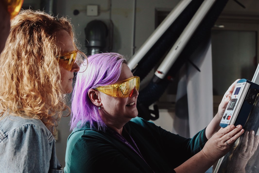 Två personer med skyddsglasögon står i ett laboratorium och mäter solljus