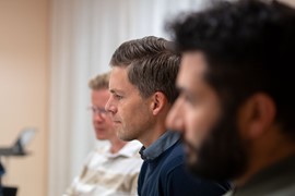 En grupp män sitter vid ett bord med bärbara datorer.